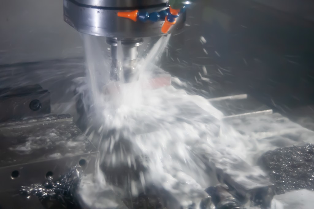 CNC milling operation cutting metal under a stream of coolant.