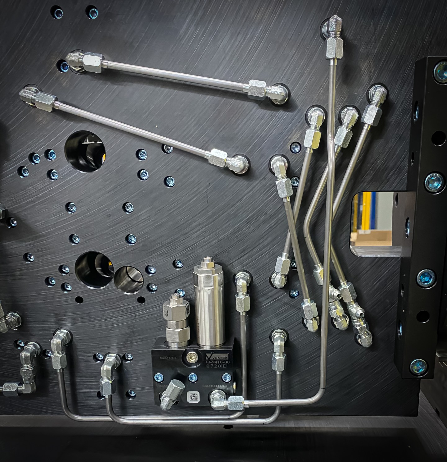 Organized stainless steel tubing and fittings on a fixture control panel.