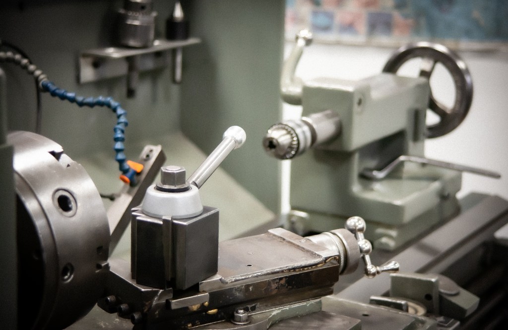 Close view of a manual metal lathe, chuck, and tool post.