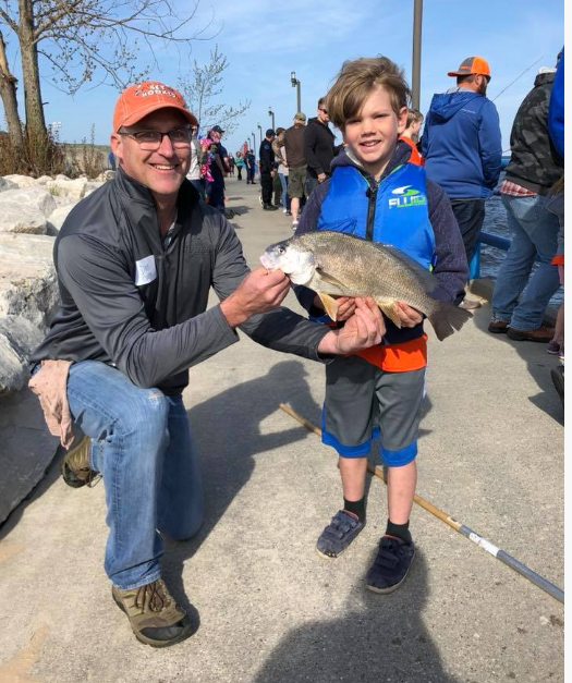 Adult and child holding a fish at a Pursuing a Dream community event.