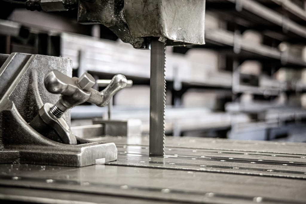 Vertical band saw blade cutting a metal workpiece.