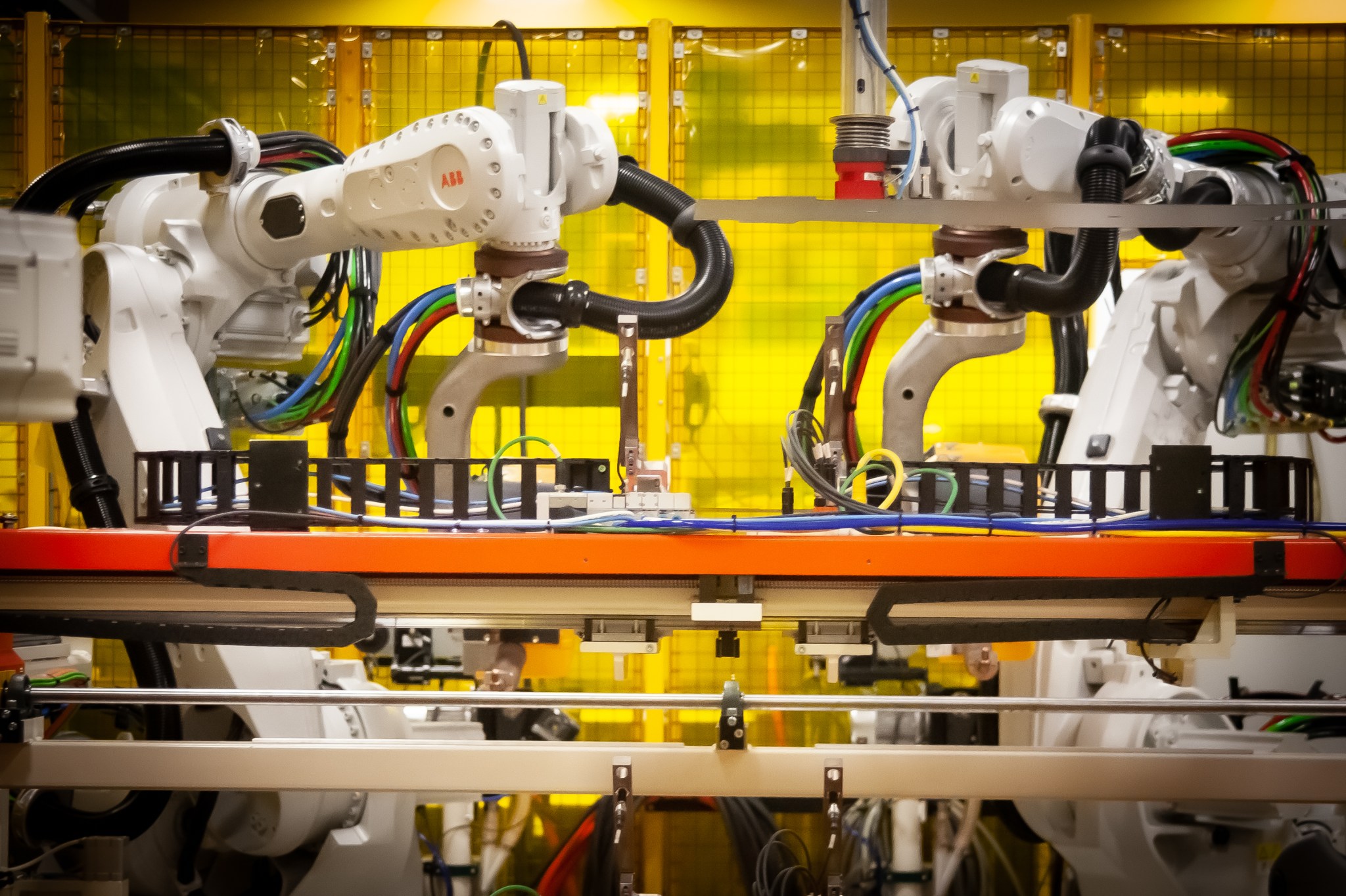 Two industrial robots working across an automotive assembly line