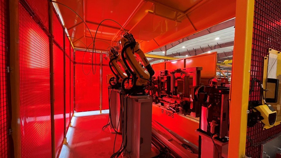 Robotic weld cell in operation with red welding light